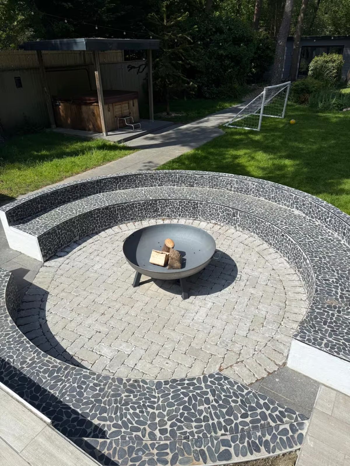 Sunken fire pit with a fire bowl and curved pebble seating